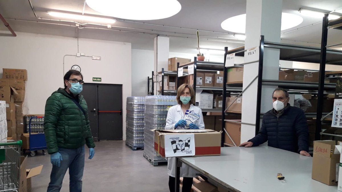 Dos miembros de la Asociación entregando material en la Milagrosa.-HDS
