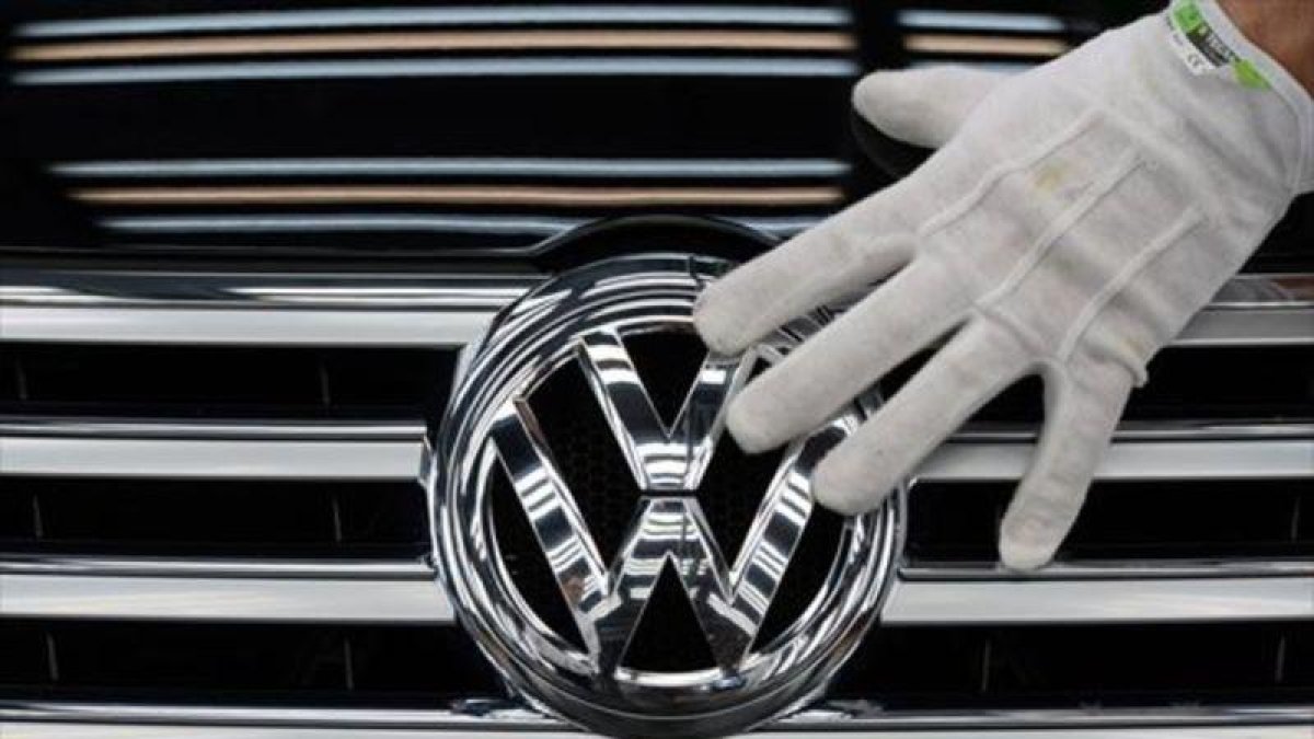 Un empleado coloca el logotipo de Volkswagen a un vehículo.-AFP / RALF HIRSCHBERGER
