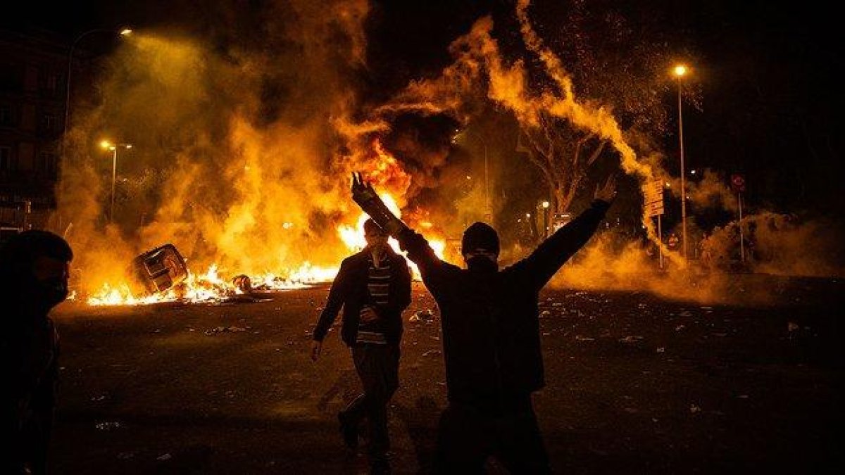 Un manifestante levanta los brazos junto a una hoguera durante la sexta noche de disturbios en Barcelona, este sábado en la plaza de Urquinaona.-DAVID ZORRAKINO
