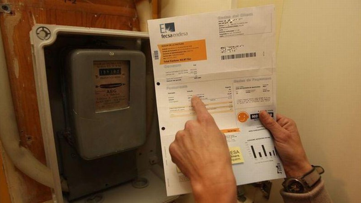 Consulta de un recibo de la luz, junto a un contador.-EL PERIÓDICO