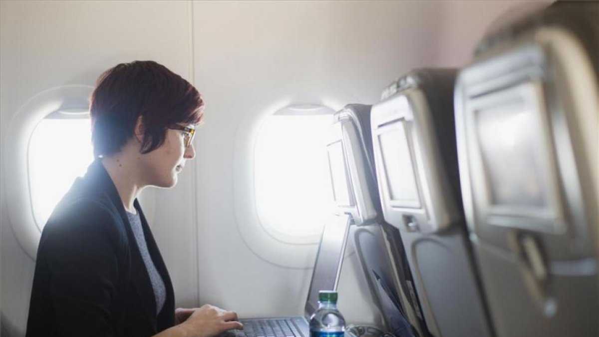 Una usuaria navega por internet a través de wifi en un avión con su portátil.-