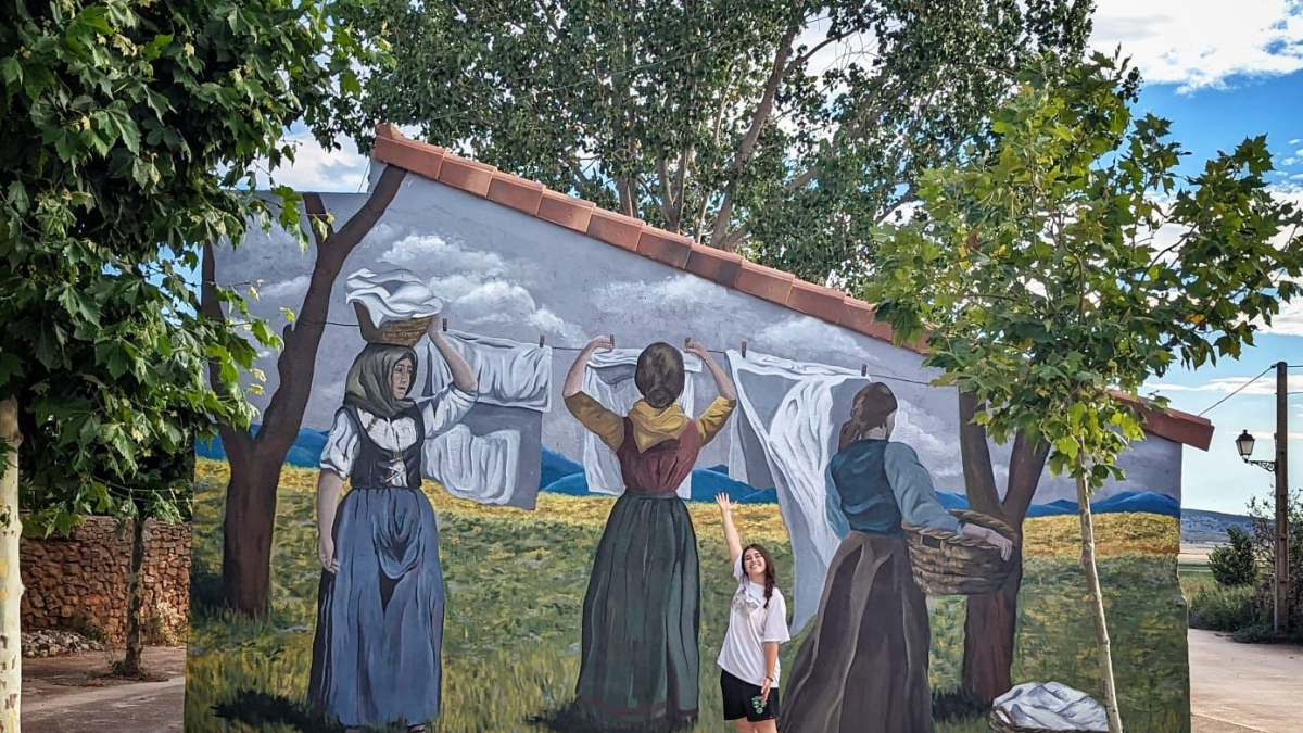 Paula García Rubio junto al mural que ha pintado en Villar del Campo.