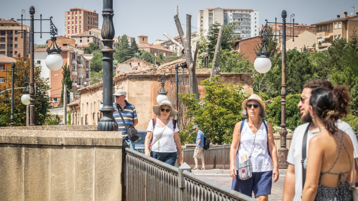 Turistas cruzando el puente de piedra.