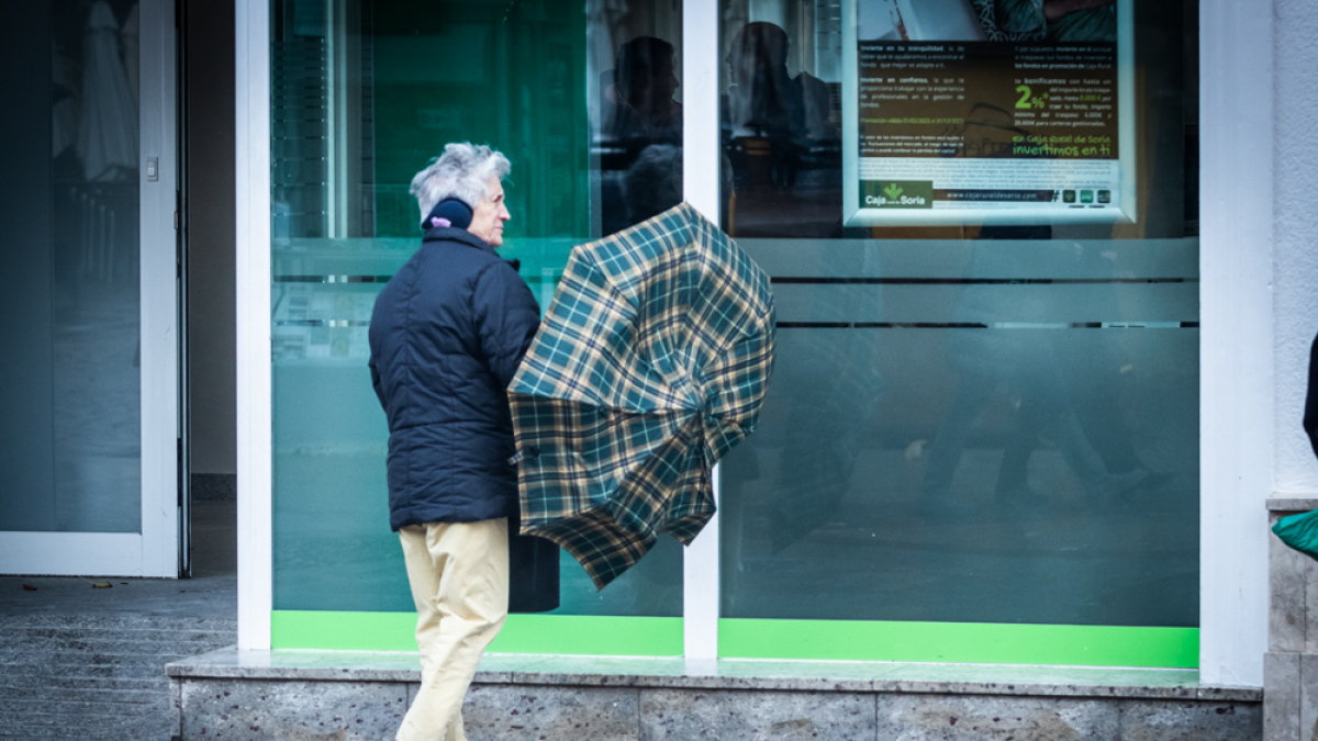 Imagen de archivo de un hombre luchando contra el viento con paraguas.