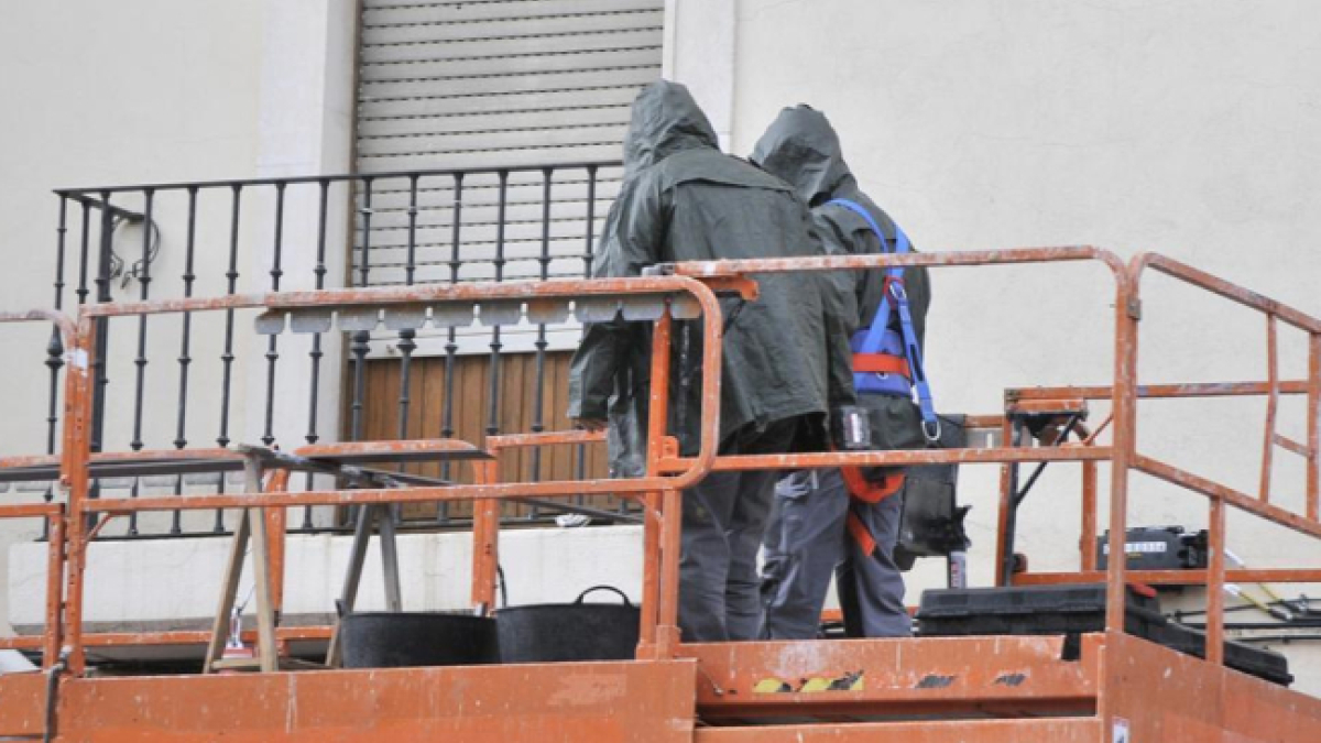 Dos trabajadores subidos en un andamio