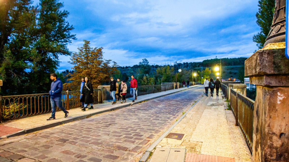 Varias personas transitan por el puente de piedra de Soria.