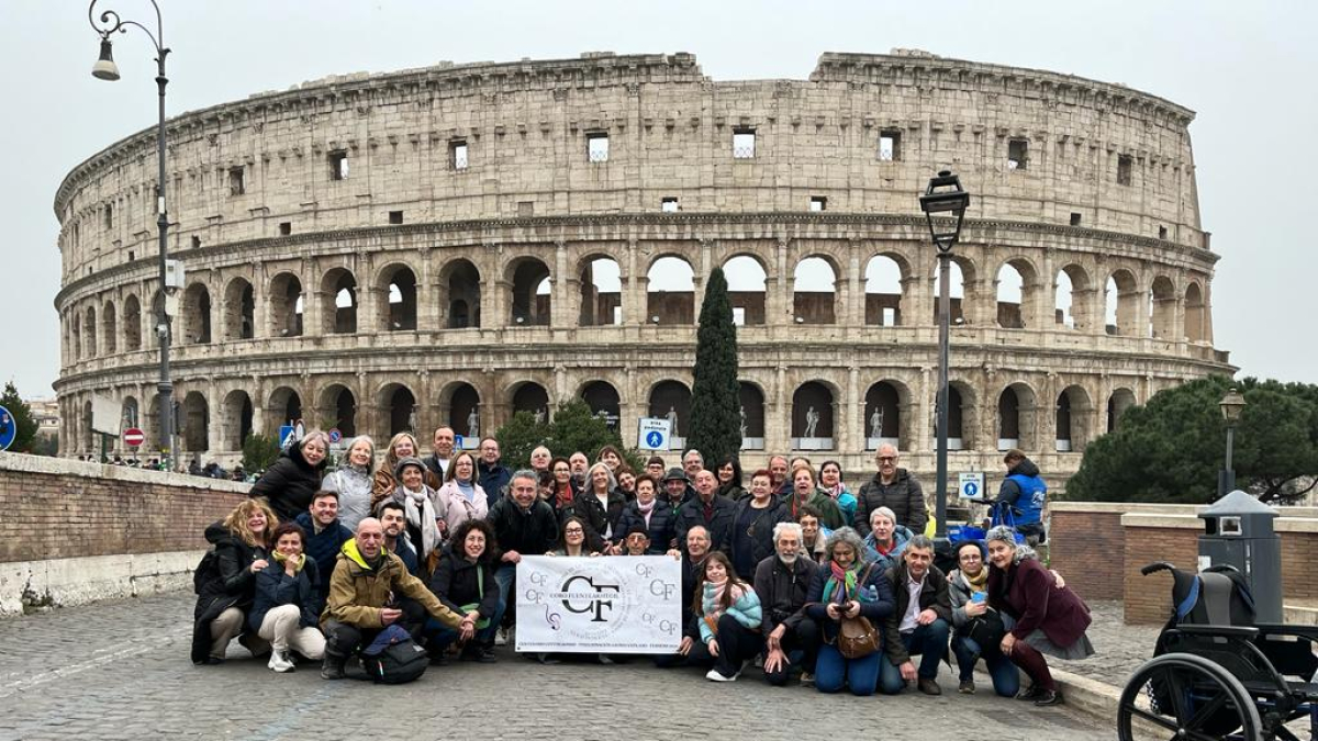 Los integrantes del coro y sus acompañantes posan ante el Coliseo.