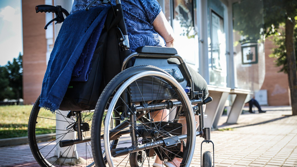 Una mujer en silla de ruedas frente a una parada de autobús.