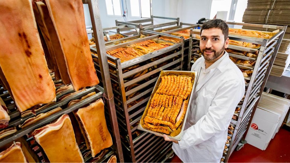 Pablo Romero posa entre pancetas frescas y torreznos recién prefritos en la fábrica.
