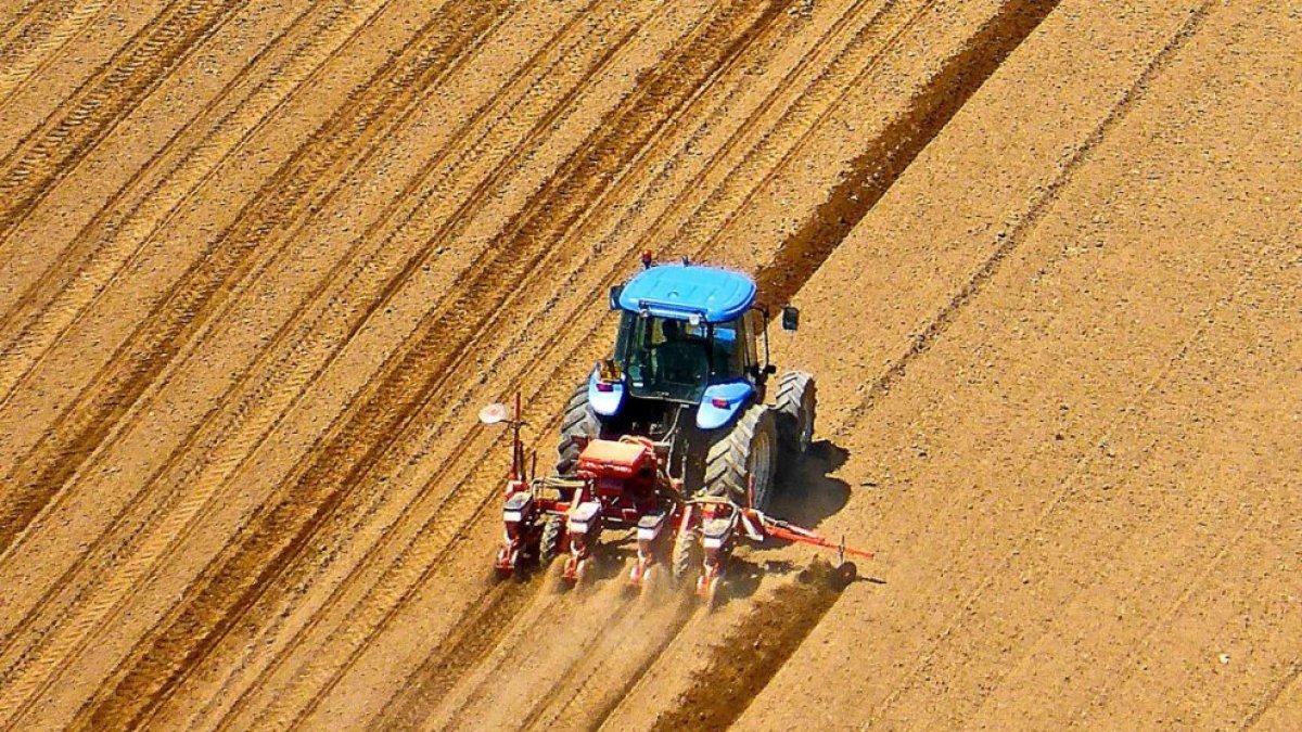 Un agricultor ara un campo de cultivo con su tractor para proceder a la sementera.