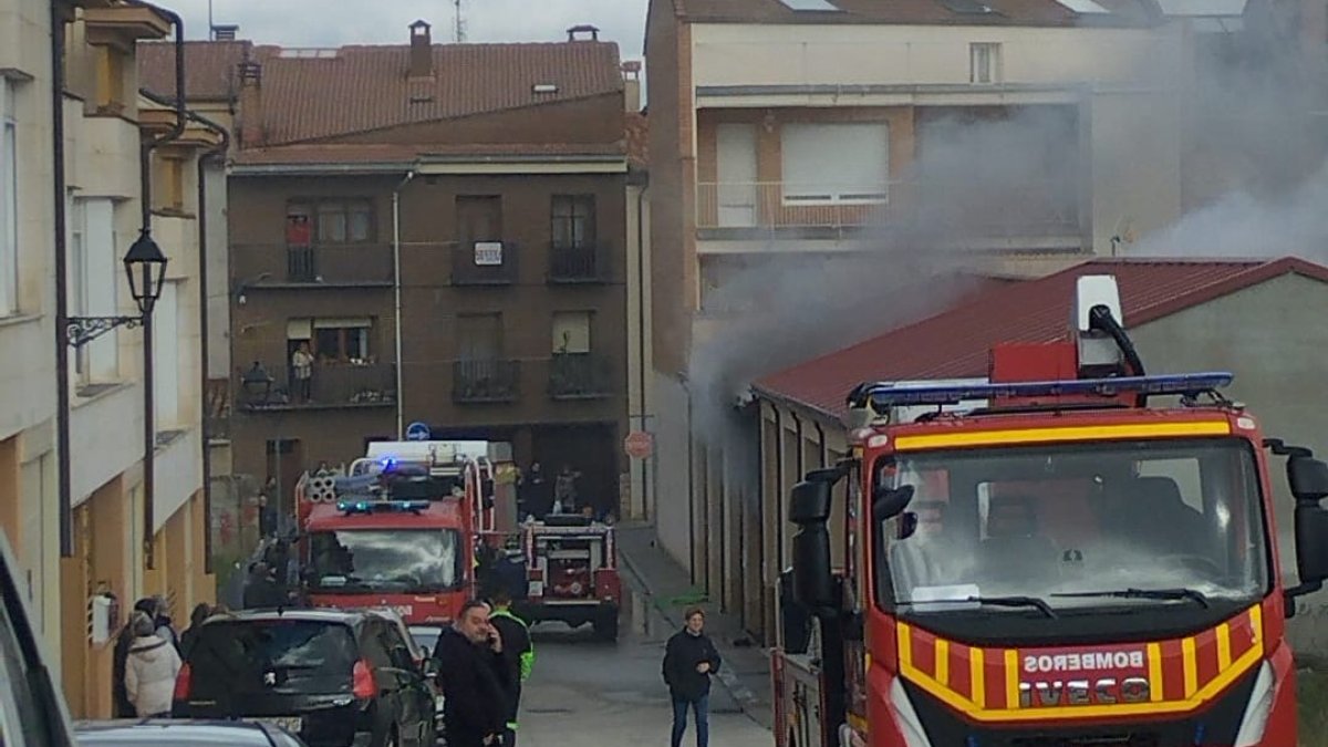 Los bomberos intervienen en la cochera incendiada, de la que sale bastante humo.