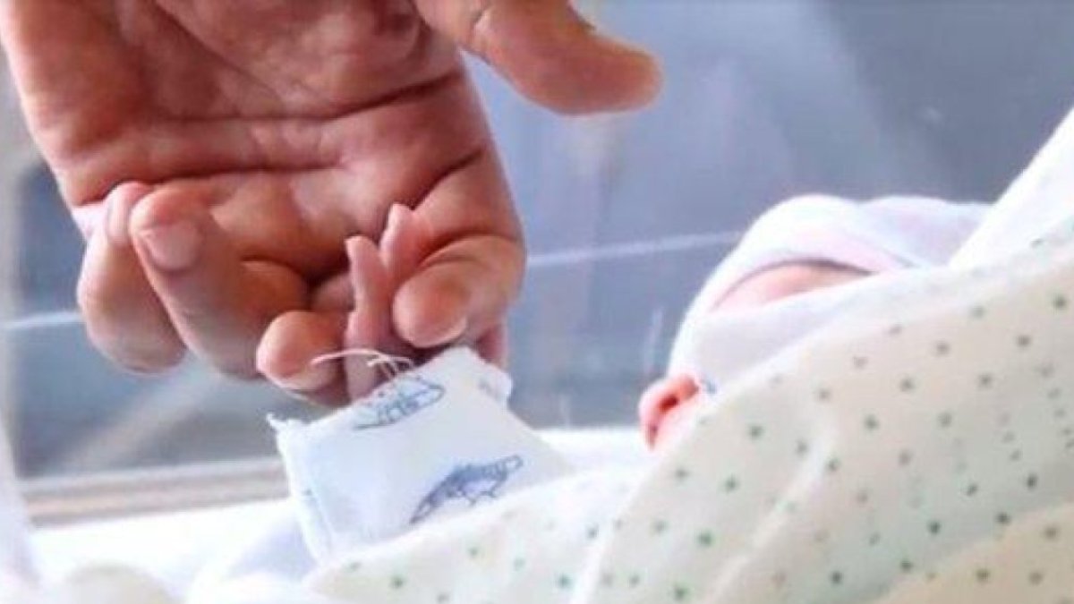 Un bebé recién nacido coge la mano de uno de sus padres.