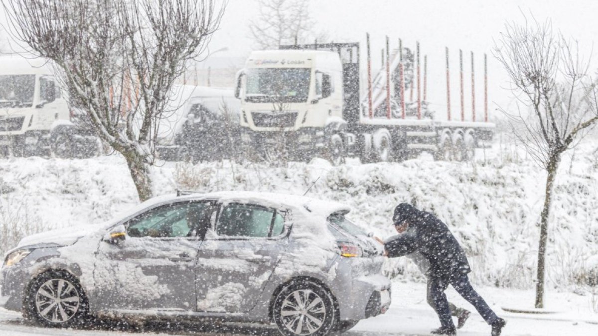 Dos personas empujan un coche durante el paso de la borrasca 'Juan'.