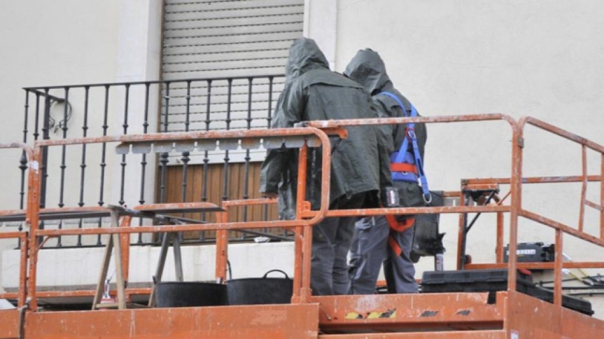 Dos trabajadores subidos en un andamio.