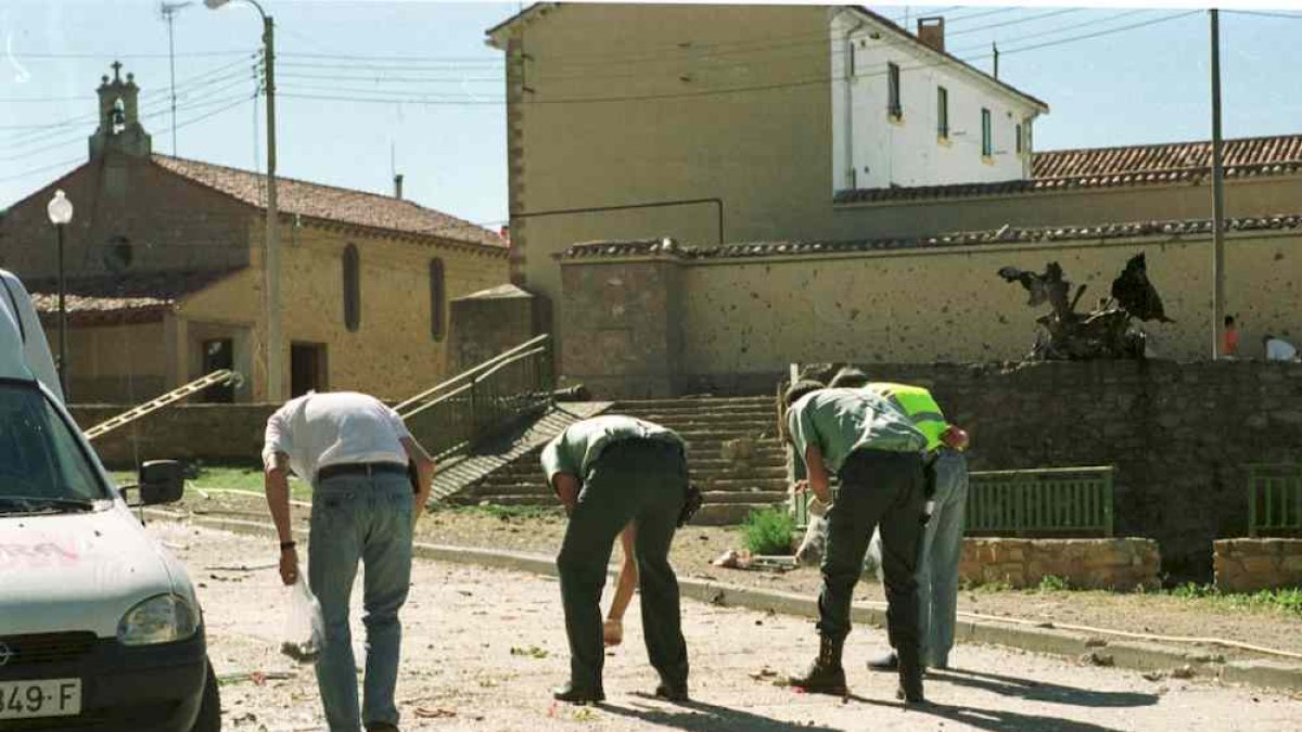 Miembros de la guardia civil recogiendo restos de explosivos con el coche bomba y la casa cuartel al fondo.
soria 16/7/00 atentado de agreda Goyo gonzalo