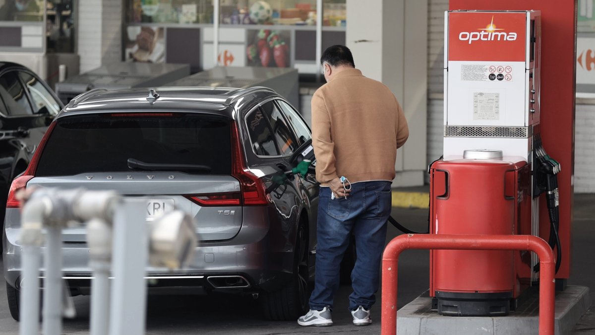 Una persona reposta combustible, en un coche, en una gasolinera.