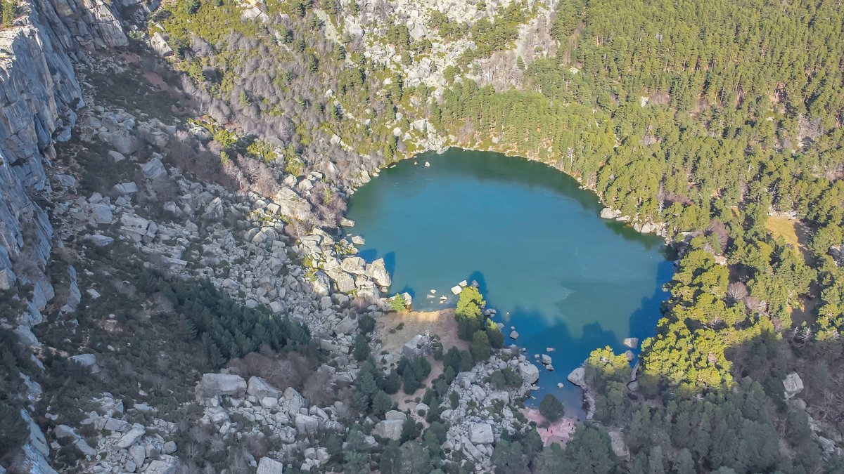 La Laguna Negra, desde el aire: un espejo glaciar oculto entre montañas, rocas y bosque espeso en el corazón del parque natural soriano