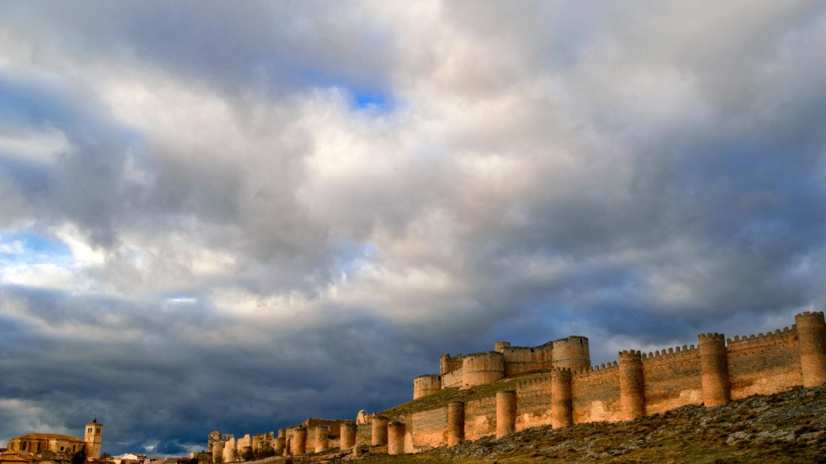 Vista panorámica del castillo de Berlanga de Duero con su doble muralla bajo un cielo dramático al atardecer.
