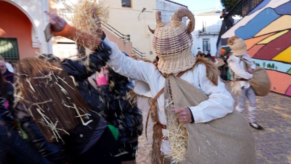 Un zarrón, con su cesta de mimbre y el saco lleno de paja, reparte manojos entre los vecinos en pleno Carnaval de Borobia, una de las tradiciones más singulares de Soria.