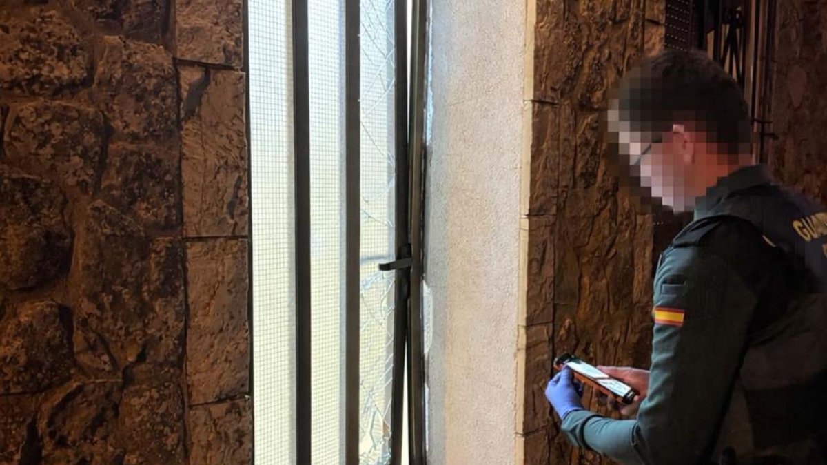 Un agente ante una de las viviendas de Barahona en la que destrozaron la puerta de entrada.