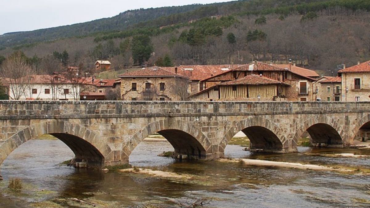 El Puente de los Carreteros, en Salduero, cruza el Duero frente a las tradicionales casonas de piedra de la comarca de Pinares.
