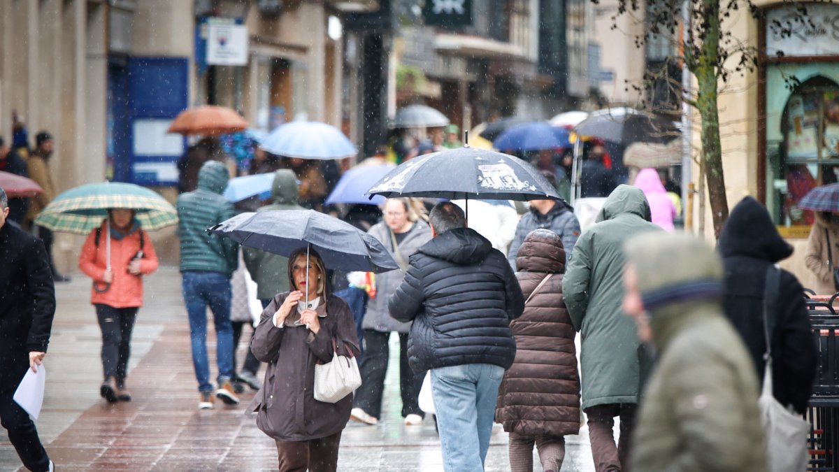 Paraguas y capuchas en el centro de Soria ante la abundante lluvia en la mañana de este viernes.