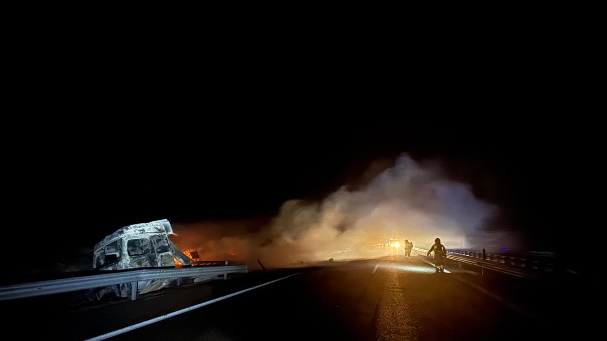 Los bomberos intentan apagar el incendio del tráiler cargado de mercancías peligrosas tras sufrir un accidente.
