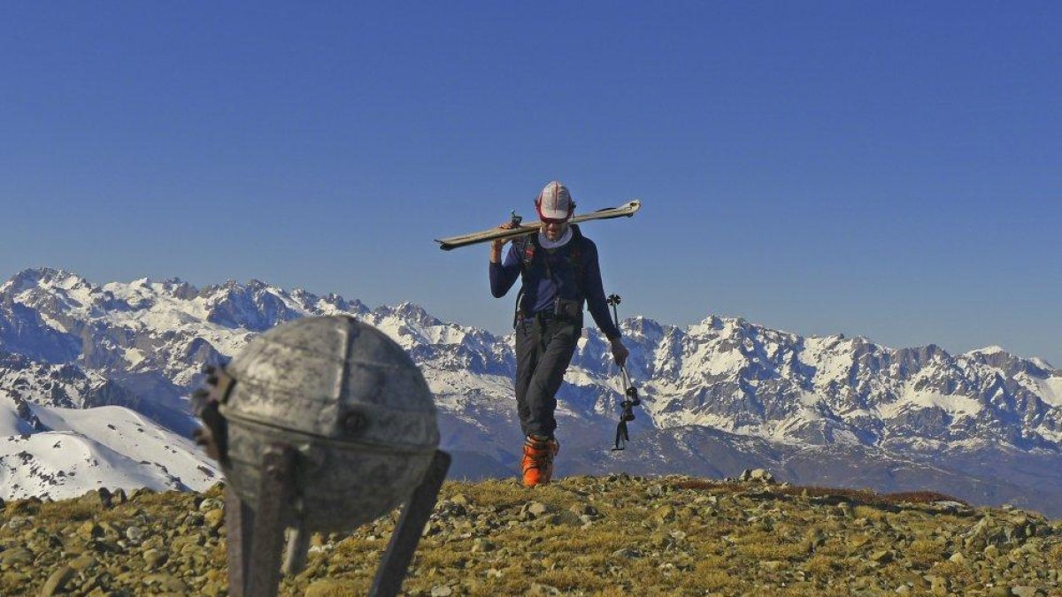 Un montañero alcanza la cumbre del Pico Lezna con los Picos de Europa al fondo.