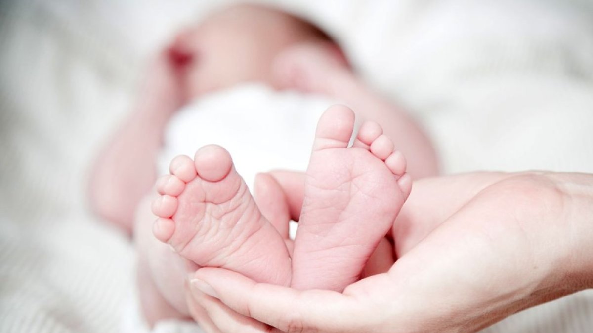 Una madre sujeta los pies de su bebé recién nacido. PQS / CCO