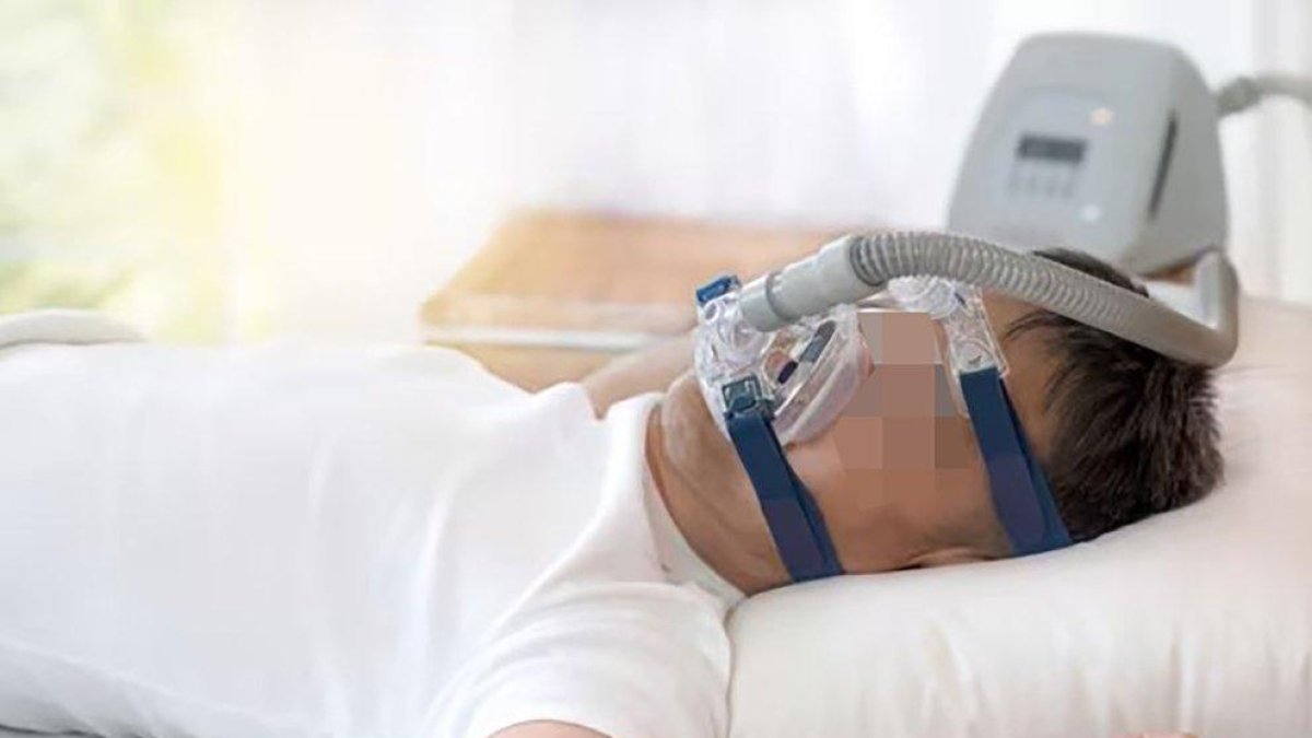 Un hombre con un comprensor de aire utilizado por la Apnea del Sueño.