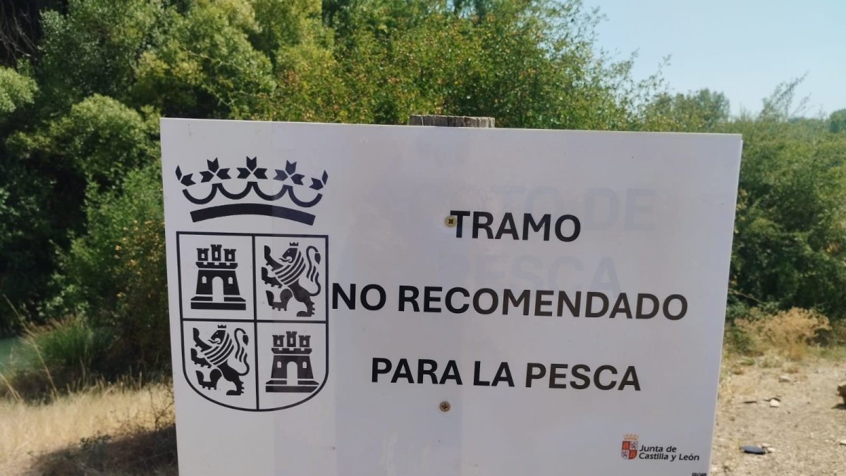 Cartel que anuncia la no recomendación de pesca en el río.