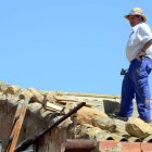 Uno de los vecinos arreglando los destrozos en el tejado de su nave-A. M.