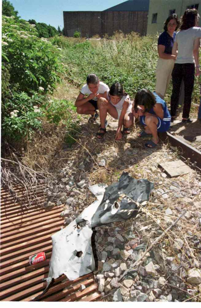Personas mirando la metralla del coche que explotó.